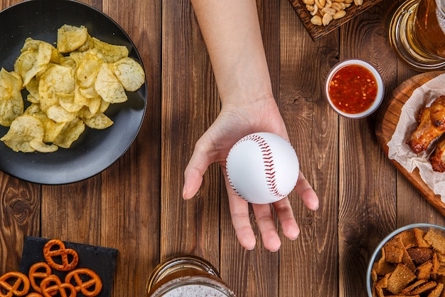 Foto oben auf Tisch mit Snacks, Hände mit Baseball