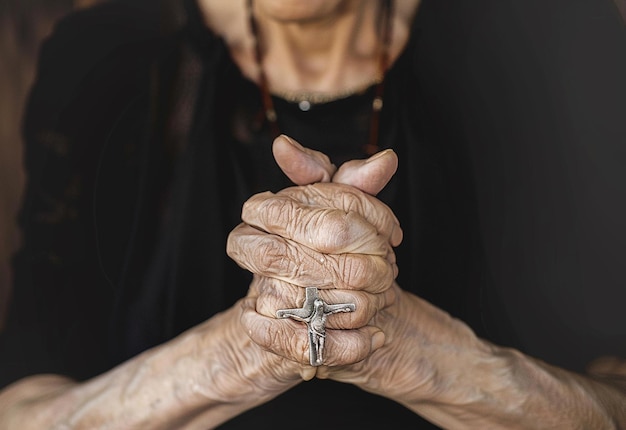 Foto de oraciones cristianas con las manos sosteniendo la cruz mientras rezan