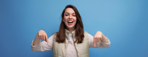 Foto foto panorâmica de uma mulher encantadora apontando dedos para baixo em propaganda em fundo azul com