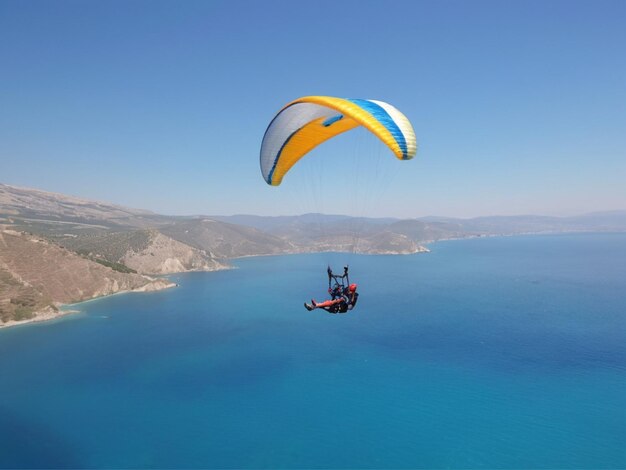Foto foto parapente em tándem voando sobre a costa do mar com água azul e céu no horizonte vista de parapente