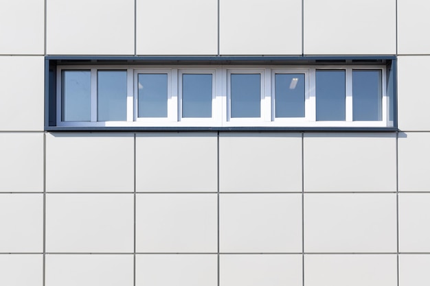 Foto de una pared blanca de una casa con plazas y pequeñas ventanas en la calle