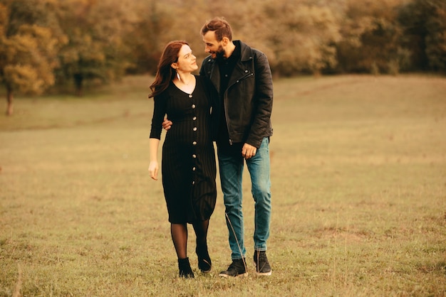 Foto de pareja embarazada, caminando en el parque y mirando el uno al otro