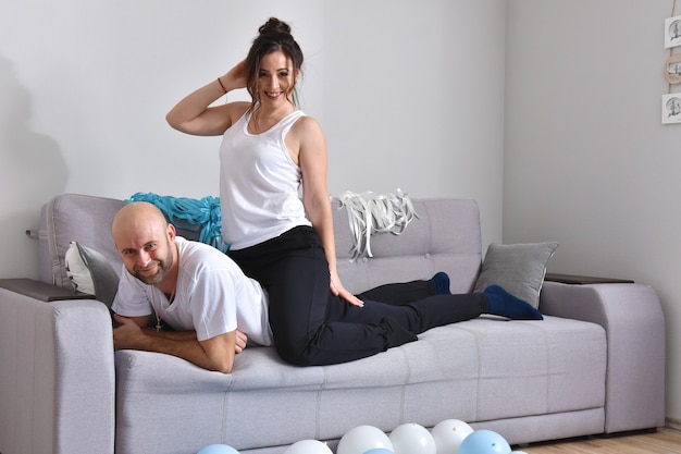 Foto de pareja de familia caucásica romántica alegre sonriendo y abrazándose mientras está sentado en el sofá en casa. Hombre y mujer, enamorado