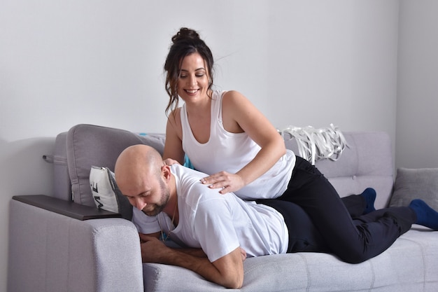 Foto de pareja de familia caucásica romántica alegre sonriendo y abrazándose mientras está sentado en el sofá en casa. Hombre y mujer, enamorado