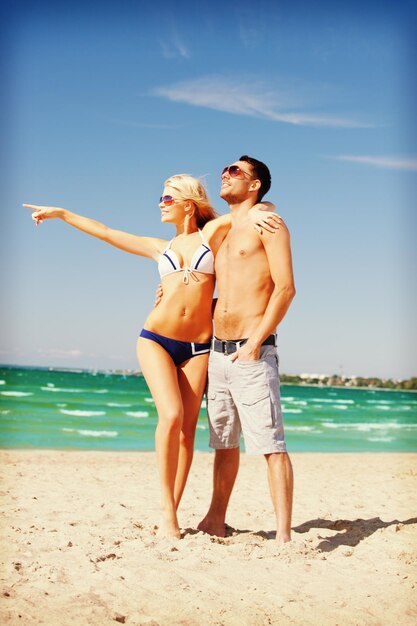 foto de una pareja feliz con gafas de sol en la playa