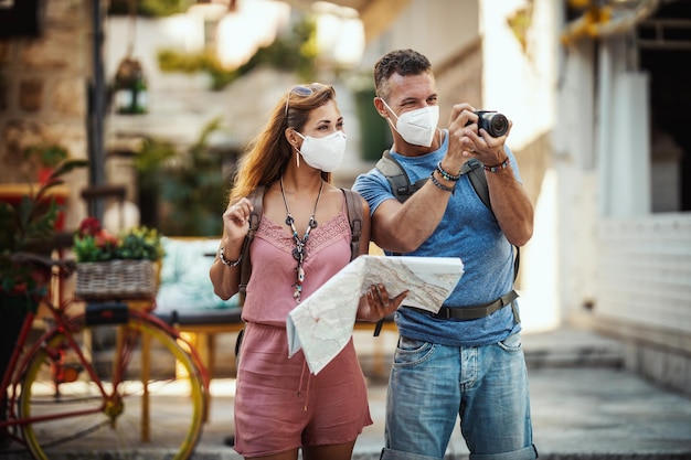 Foto de una pareja feliz con máscara protectora N95 pasando tiempo de vacaciones y explorando una ciudad mediterránea en la pandemia de la corona.