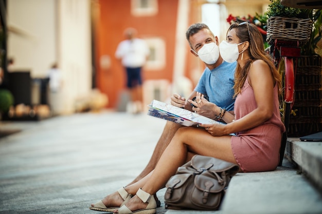 Foto de una pareja feliz con máscara protectora N95 pasando tiempo de vacaciones y explorando una ciudad mediterránea en la pandemia de la corona.