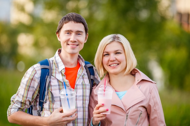 Foto de pareja - hombre y mujer con batidos en el parque en verano