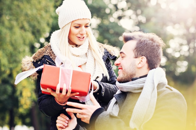 Una foto de una pareja joven con un regalo en el parque.