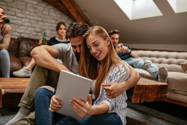 Una foto de una pareja joven sentada en el suelo mirando una tableta