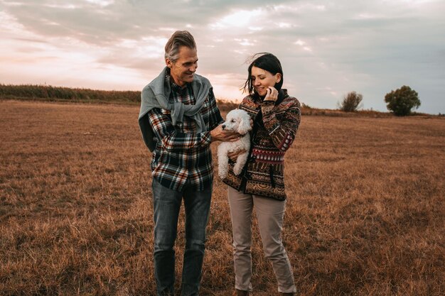 Una foto de una pareja de mediana edad disfrutando de un día en la naturaleza con su perro