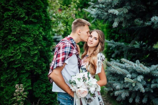 Foto de pareja en ropa elegante besándose en el parque el día de verano.