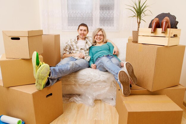 Foto de una pareja sentada en un sofá entre cajas de cartón