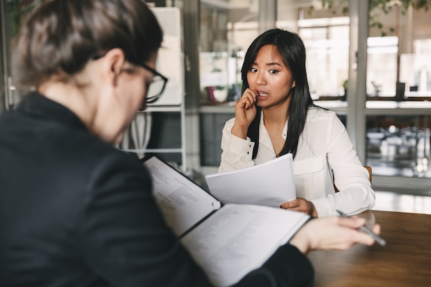 Foto de la parte posterior de la entrevista de negocios y lectura del currículum de la solicitante nerviosa durante la entrevista de trabajo: concepto de negocio, carrera y colocación