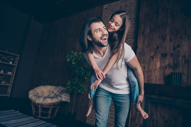 Foto de pequeña divertida niña enérgica emocionado guapo papá llevar hija a cuestas jugando juegos de buen humor pasar tiempo libre