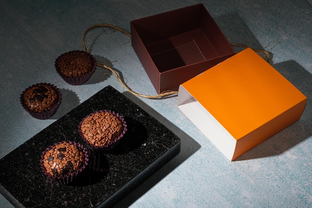 Foto de bajo perfil Brigadeiros dispuestos sobre una piedra de mármol negro brillante junto a una caja con vista al lado de la cuerda de sisal