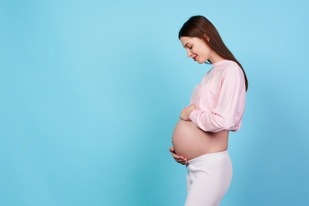 Foto de perfil de una encantadora y dulce niña embarazada de 9 meses se encuentra de lado