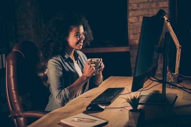 Foto de perfil de hermosa mujer de negocios de piel oscura beber café caliente en el lugar de trabajo