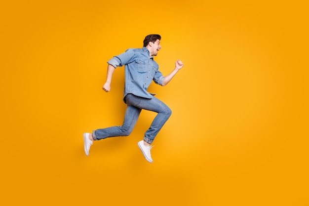 Foto de perfil lateral del hombre positivo alegre gritando después de ver el comienzo de las ventas aislado en calzado blanco sobre la pared de colores vivos