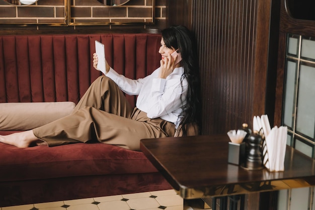 Foto de perfil lateral de una mujer de negocios hablando por teléfono mujer de negocios sentada en un sofá en un acogedor café