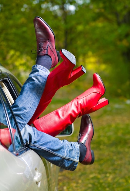 Foto pierna hombre y mujer fuera del coche sobre un fondo de naturaleza