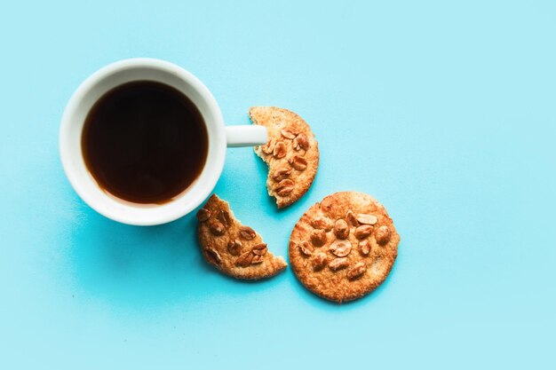 Foto plana com xícara de café e biscoitos com nozes em fundo azul