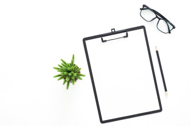 Foto foto plana creativa del escritorio del espacio de trabajo mesa de oficina de vista superior con gafas, lápiz, cartón de recortes en blanco y planta sobre fondo de color blanco vista superior con espacio de copia fotografía plana