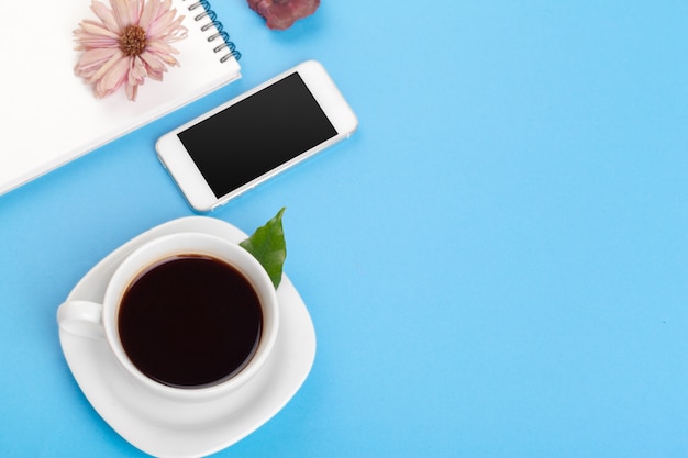 Foto plana con cuaderno, taza de café en azul