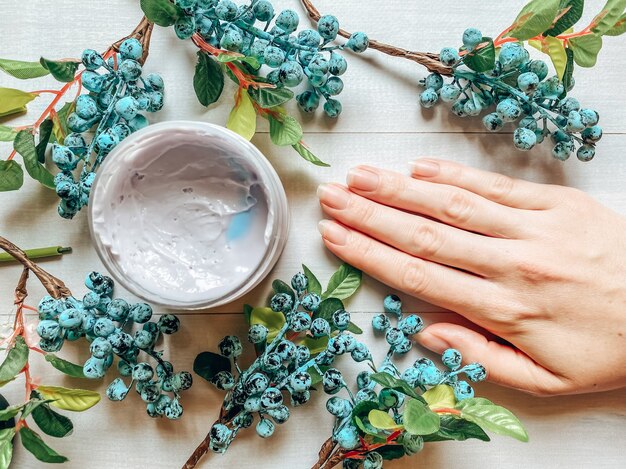 Foto plana de um produto cosmético cremoso em uma garrafa e uma mão feminina. Cremes e loções cosméticas, produtos para os cuidados da pele.