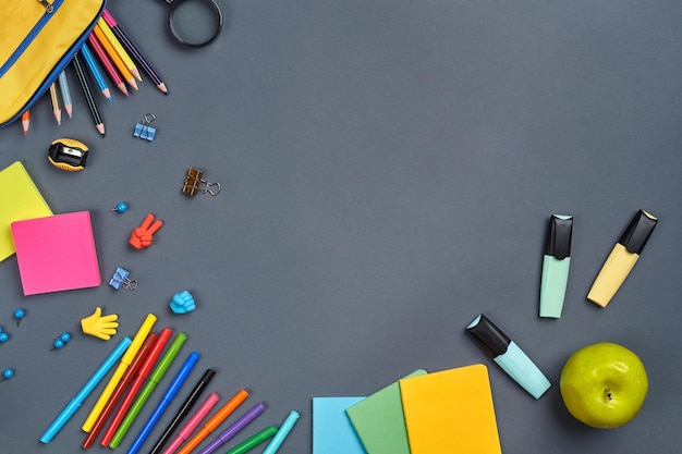 Foto plana del escritorio del espacio de trabajo con accesorios escolares o suministros de oficina sobre fondo gris