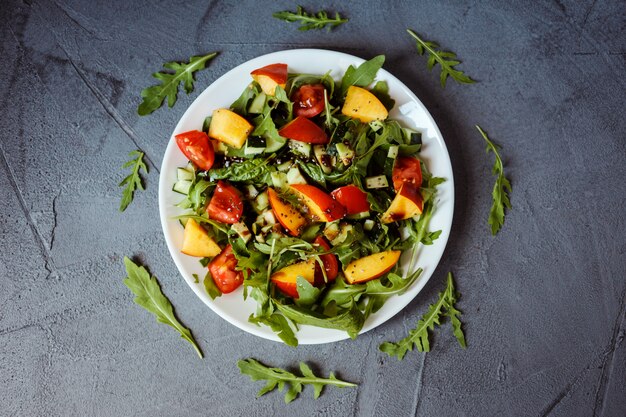 Foto plana leiga de salada colorida saudável na chapa branca sobre fundo cinza.