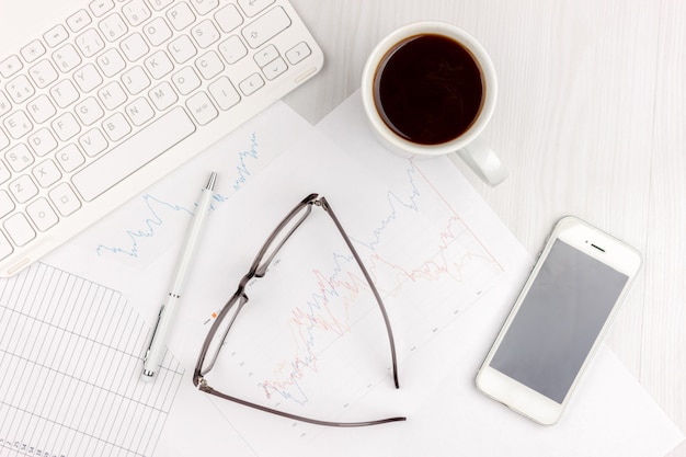 Foto plana de la posición del escritorio de oficina blanco con el ordenador portátil, el smartphone, las lentes, el cuaderno y la pluma con el fondo del espacio de la copia. Bosquejo