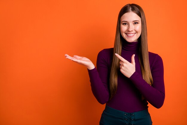 Foto positiva garota promotor segurar mão apontar dedo indicador copyspace demonstrar anúncios de venda de inverno escolha decisão escolha usar boa aparência pulôver isolado brilhante brilho cor de fundo