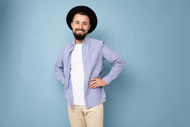 Foto de positivo feliz sonriente guapo joven brunet barbudo hombre vestido con camisa azul casual y