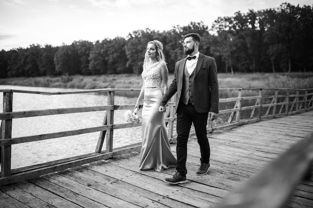 Foto preto e branco elegante casal de recém-casados posando em uma ponte no dia do casamento