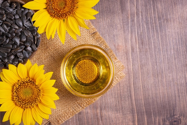 Foto del primer del aceite de girasol con las semillas en fondo de madera. Concepto de producto bio y orgánico.