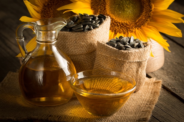 Foto del primer del aceite de girasol con las semillas en fondo de madera. Concepto de producto bio y orgánico.