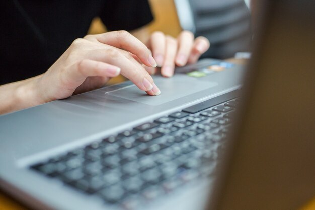 Foto del primer de las manos femeninas que mecanografían el texto en un teclado del labtop.