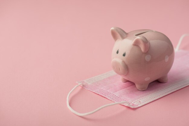 Foto de primer plano de la alcancía en máscara médica aislado fondo rosa con copyspace