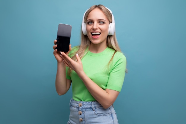 Foto de primer plano de una alegre y enérgica chica rubia con un atuendo informal con grandes auriculares blancos