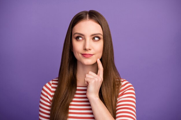 Foto de primer plano de la atractiva dama divertida peinado largo estudiante inteligente mirar lado interesado espacio vacío brazo en la barbilla usar camisa a rayas casual aislado pared de color púrpura pastel