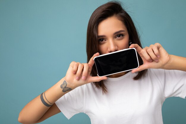 Foto en primer plano de bastante positivo joven morena apuesto vistiendo camiseta blanca de pie