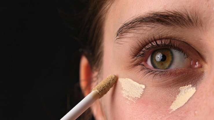 Foto una foto en primer plano de una chica aplicando corrector debajo de sus ojos y fundamento de maquillaje en sus párpados