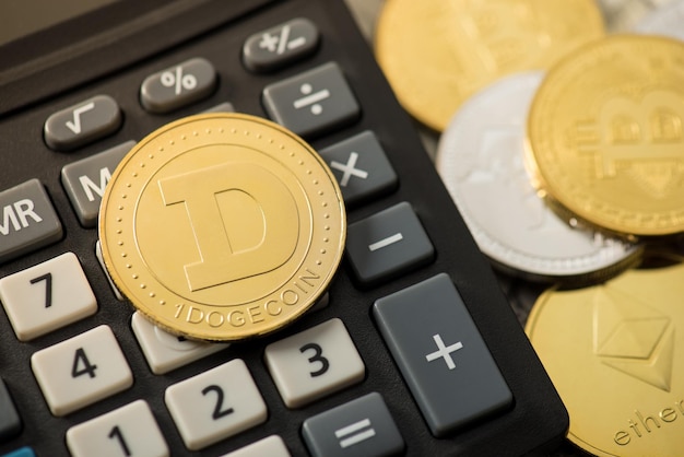 Foto de primer plano de dogecoin de oro en calculadora y monedas con símbolos de criptomoneda