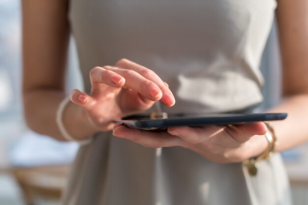 Foto de primer plano de una empresaria con tableta digital en las manos. Escritura femenina, mensajes de texto y mensajes, mediante conexión inalámbrica a internet.