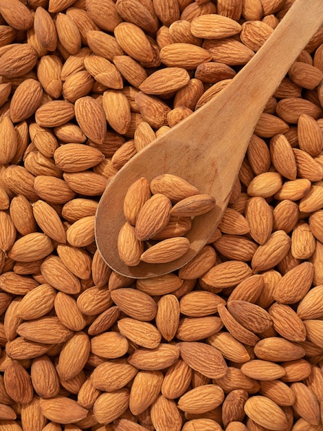 Foto de primer plano de fondo de nueces de nueces de almendra una cuchara de madera con algunas nueces en ella foto vertical