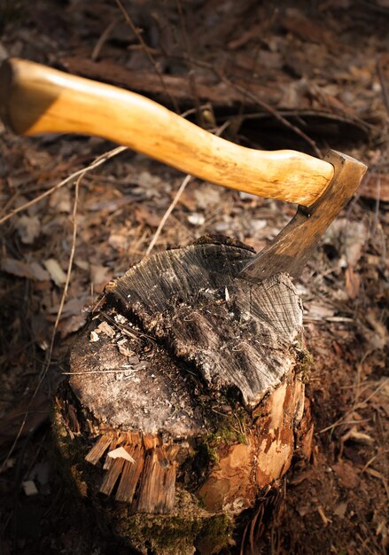 Foto en primer plano de un hacha de hierro atascada en un tronco de madera