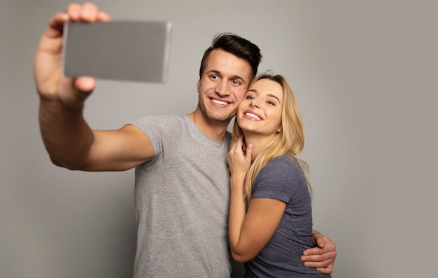 Foto foto de primer plano de una hermosa chica y un hombre atractivo en ropa casual, que se abrazan mientras posan juntos para una selfie.