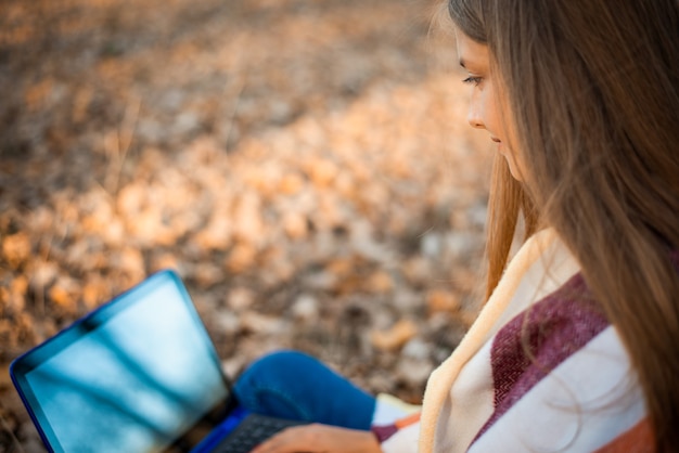 Foto foto en primer plano de la hermosa niña haciendo un trabajo en la computadora portátil en el parque