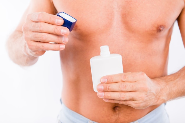 Foto en primer plano de un hombre abriendo una botella de loción